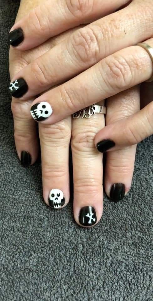 Striking Gothic Nail Design with Black Base and Edgy White Skull Motifs.