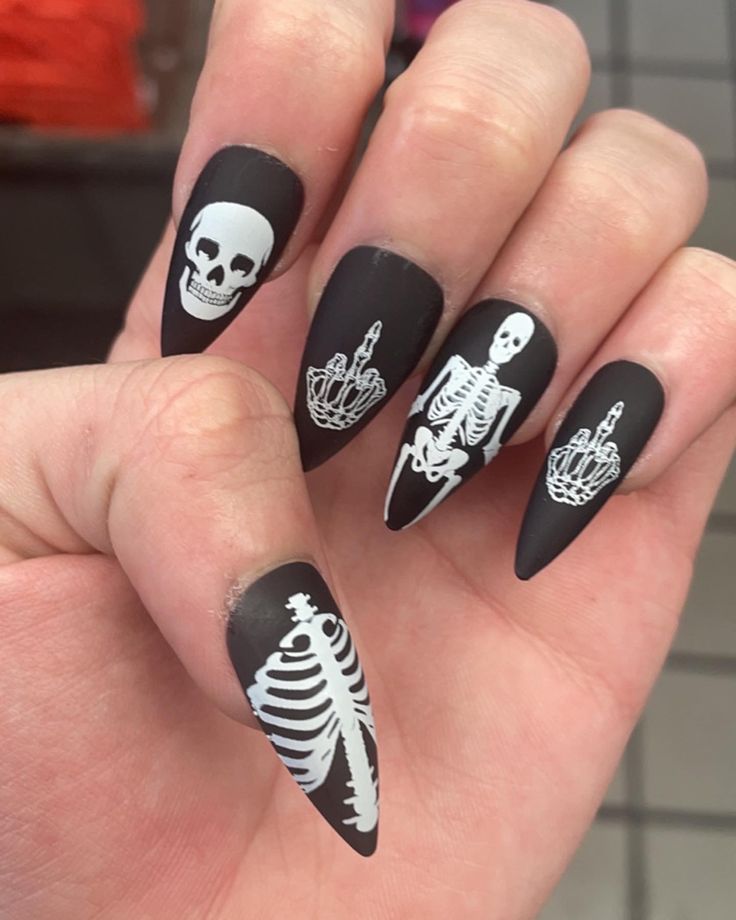 Bold Gothic Nail Design: Matte Black with Unique Skeletal Motifs for Halloween.