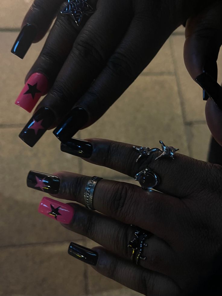 Striking Bold Nail Art: Glossy Black and Vibrant Pink Star Motifs on Long Square Nails.