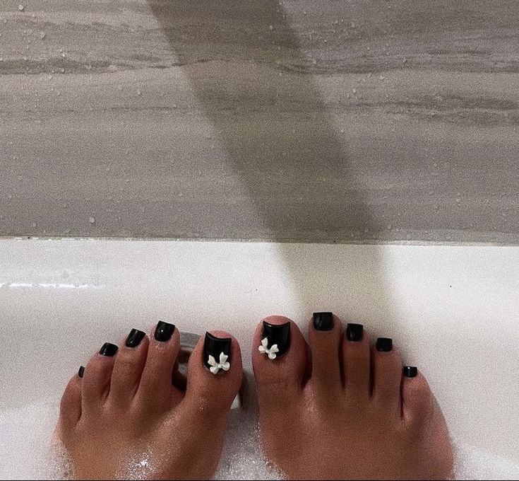 Sophisticated Black Pedicure with Delicate Floral Accents.