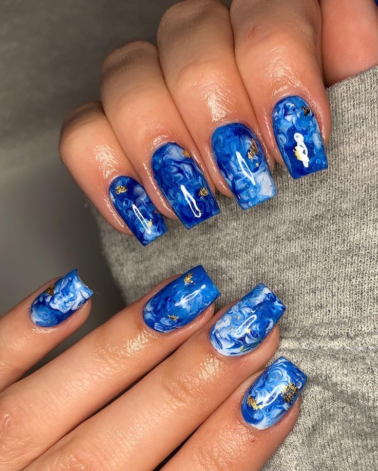 Elegant Blue Marbled Nail Design with Gold Accents and Glossy Finish.