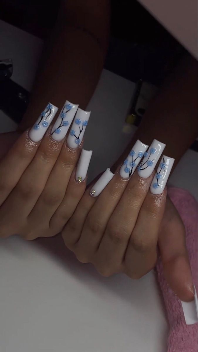 Elegant Long White Tip Nail Design with Blue Floral Patterns and Sparkling Accents.