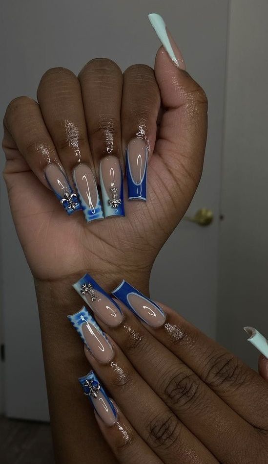 Elegant Nude and Blue Nail Design with Intricate Embellishments and Modern Shapes