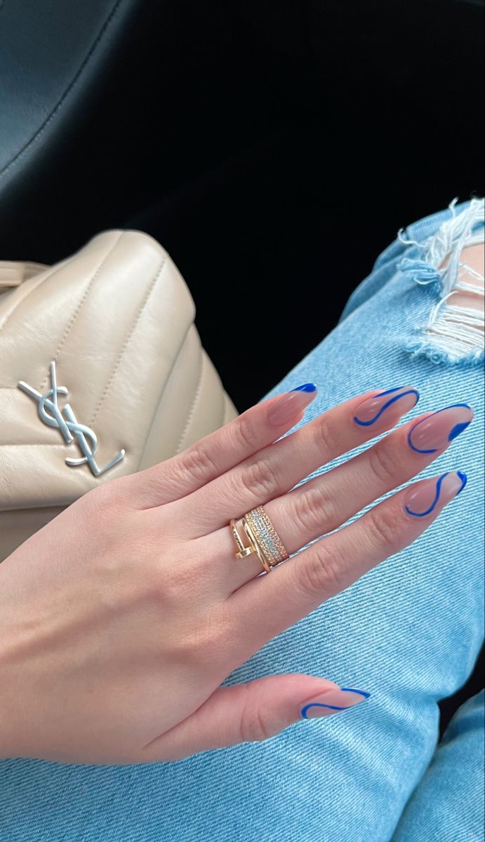 Elegant Nude and Vibrant Blue Nail Design with Curved Tips and Chic Rings.