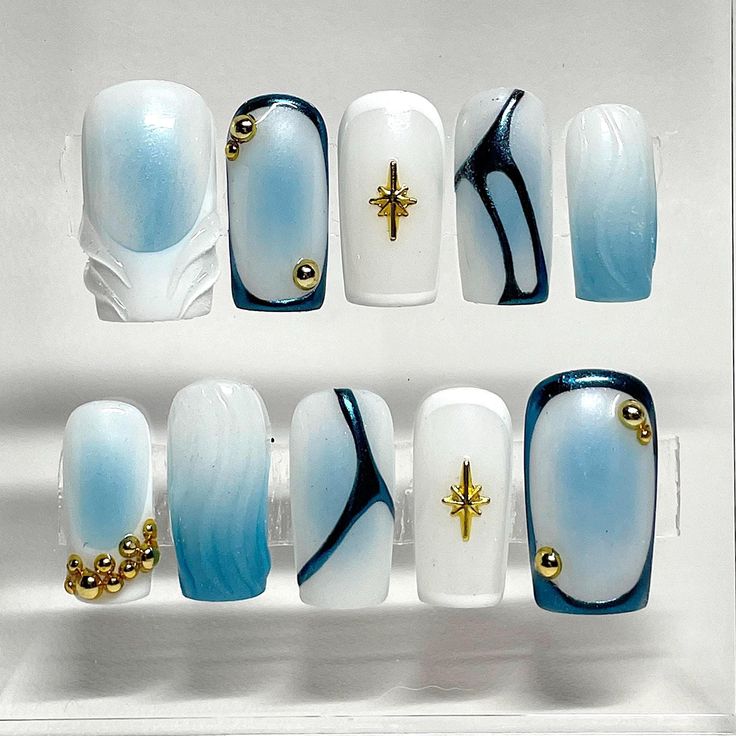 Elegant Soft Blue and White Nail Design with Metallic Gold and Intricate Black Accents.