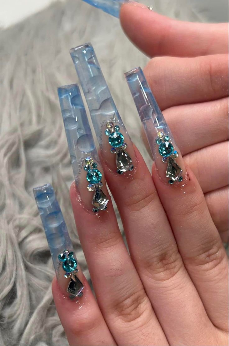 Modern Translucent Blue Long Nails Adorned with Vibrant Gemstones for a Glamorous Look.