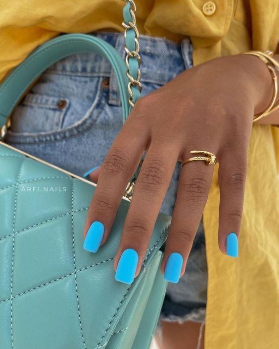 Chic Summer Aesthetic: Vibrant Blue Nails Complementing a Soft Yellow Shirt