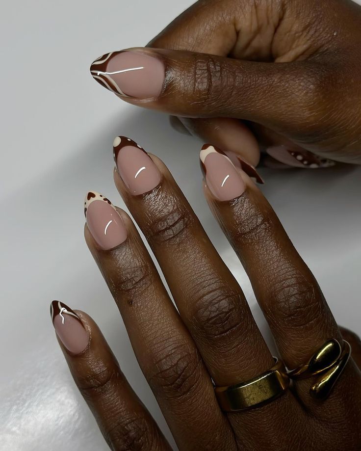 Sophisticated Nail Design: Nude and Chocolate Hues with White Accents in Almond and Pointed Shapes.