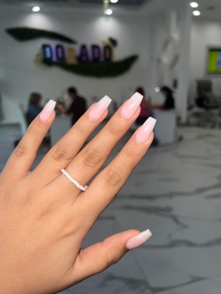 Sophisticated Soft Pink Ombre Long Nails with Elegant Finish and Accessory.