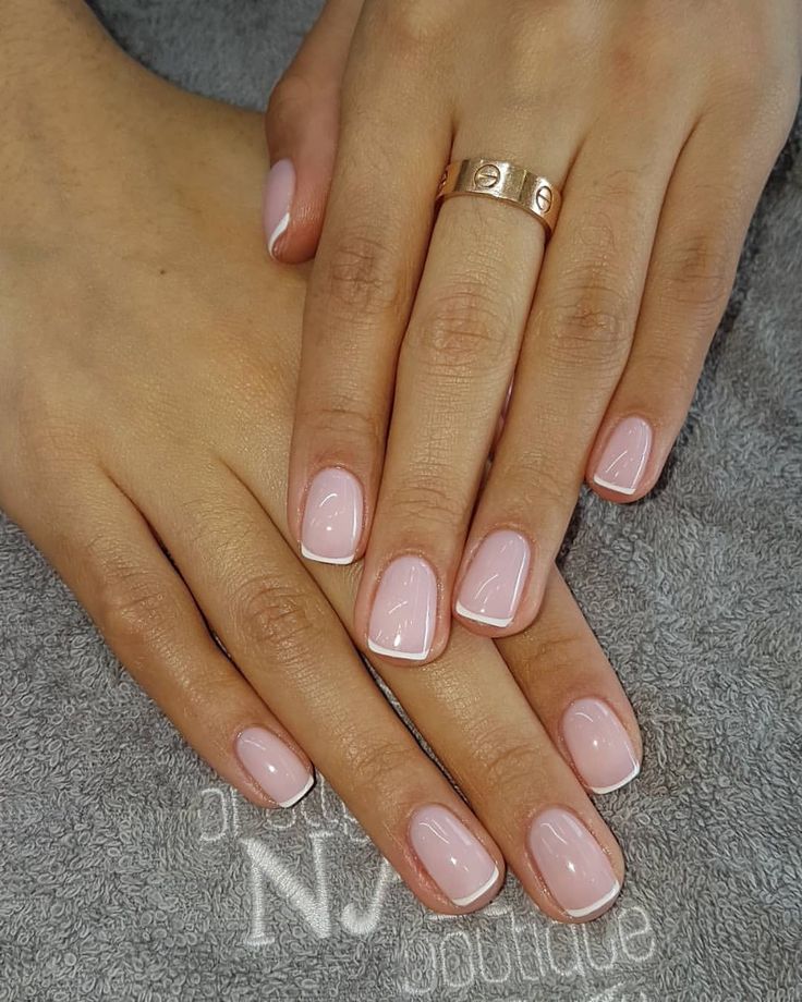 Chic Soft Pink Nail Design with Delicate White Tips and Stylish Gold Ring.