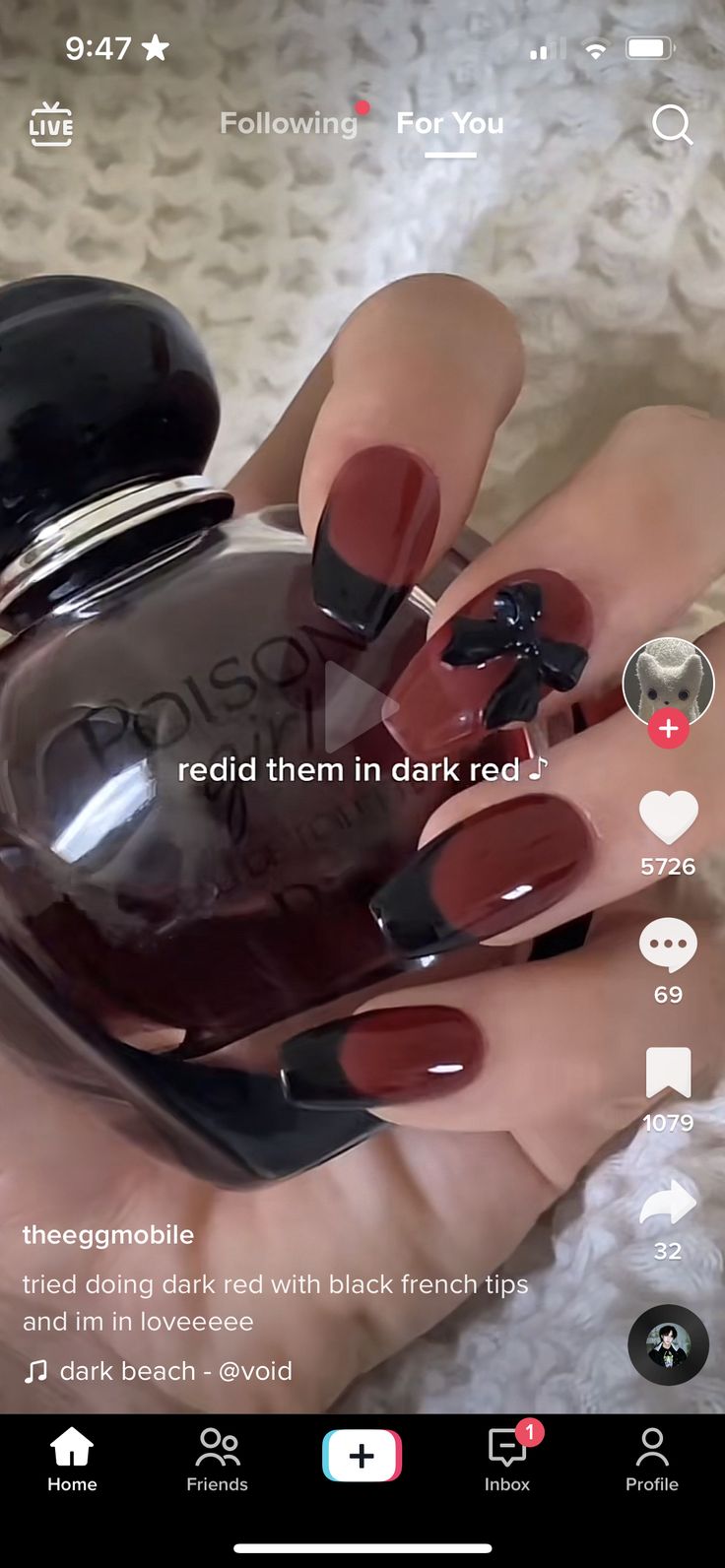 Sophisticated Deep Red Nail Design with Black French Tips and Chic Bow Accent.