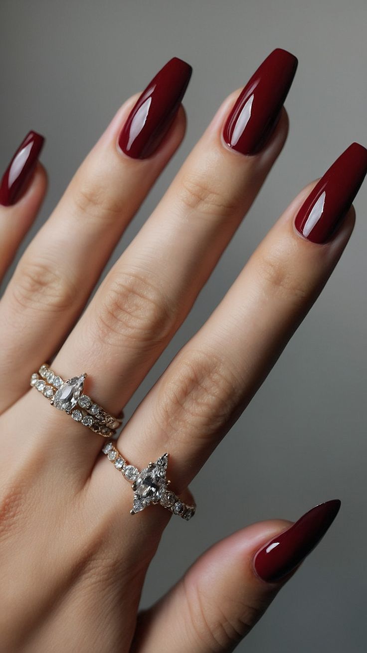 Sophisticated Crimson Manicure with Almond-Shaped Nails and Glamorous Diamond Rings.