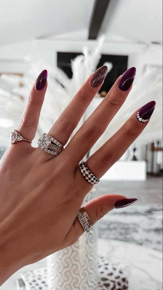 Sophisticated Deep Purple Nail Design with Glitter Accents and Rhinestones.