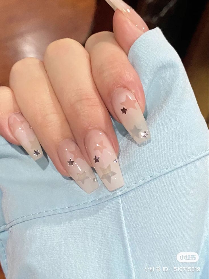 Elegant Ombre Nail Design: Nude to Creamy White with Silver Stars and Glitter Accents.