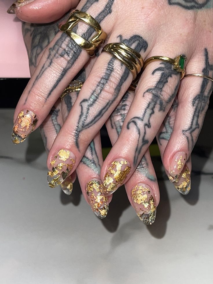 Stylish Stiletto Nail Design with Nude-Gold Accents and Bold Accessories.