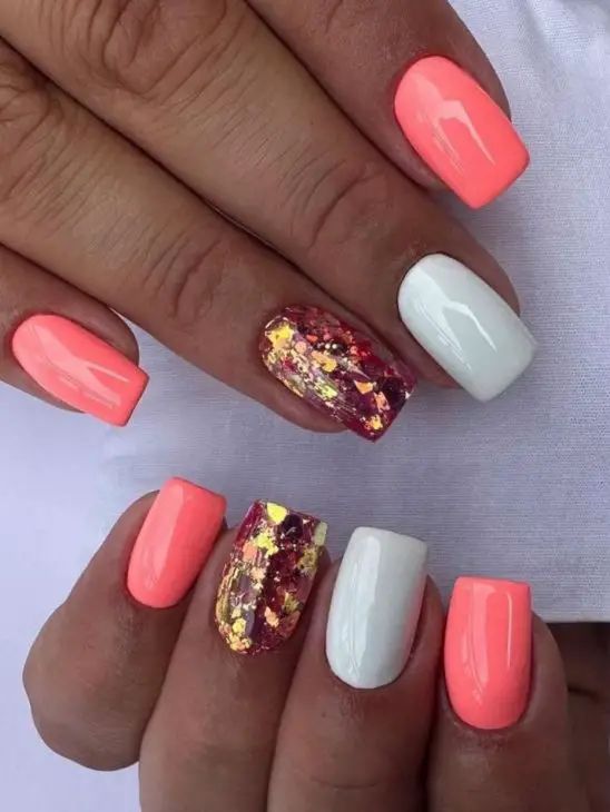 Playful Coral and White Nail Design with Glamorous Gold and Red Glitter Accents.