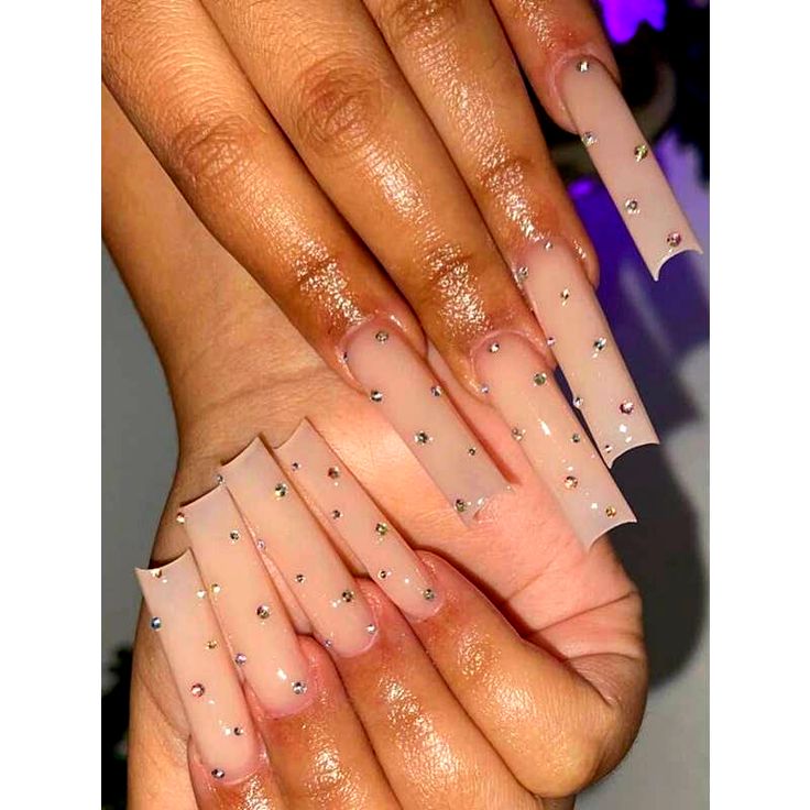 Sophisticated Nude Nail Design with Long Transparent Tips and Shimmering Rhinestones.