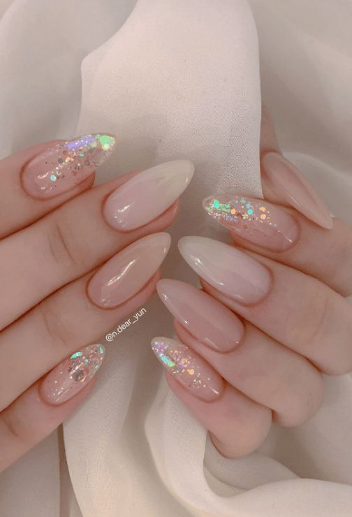 Chic Almond-Shaped Nail Design: Soft Nude Gradient with Holographic Glitter Accents for Glamorous Looks.