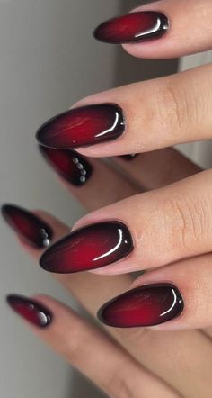 Striking Gradient Deep Red to Black Nail Design with Glossy Finish and Elegant Embellishments.