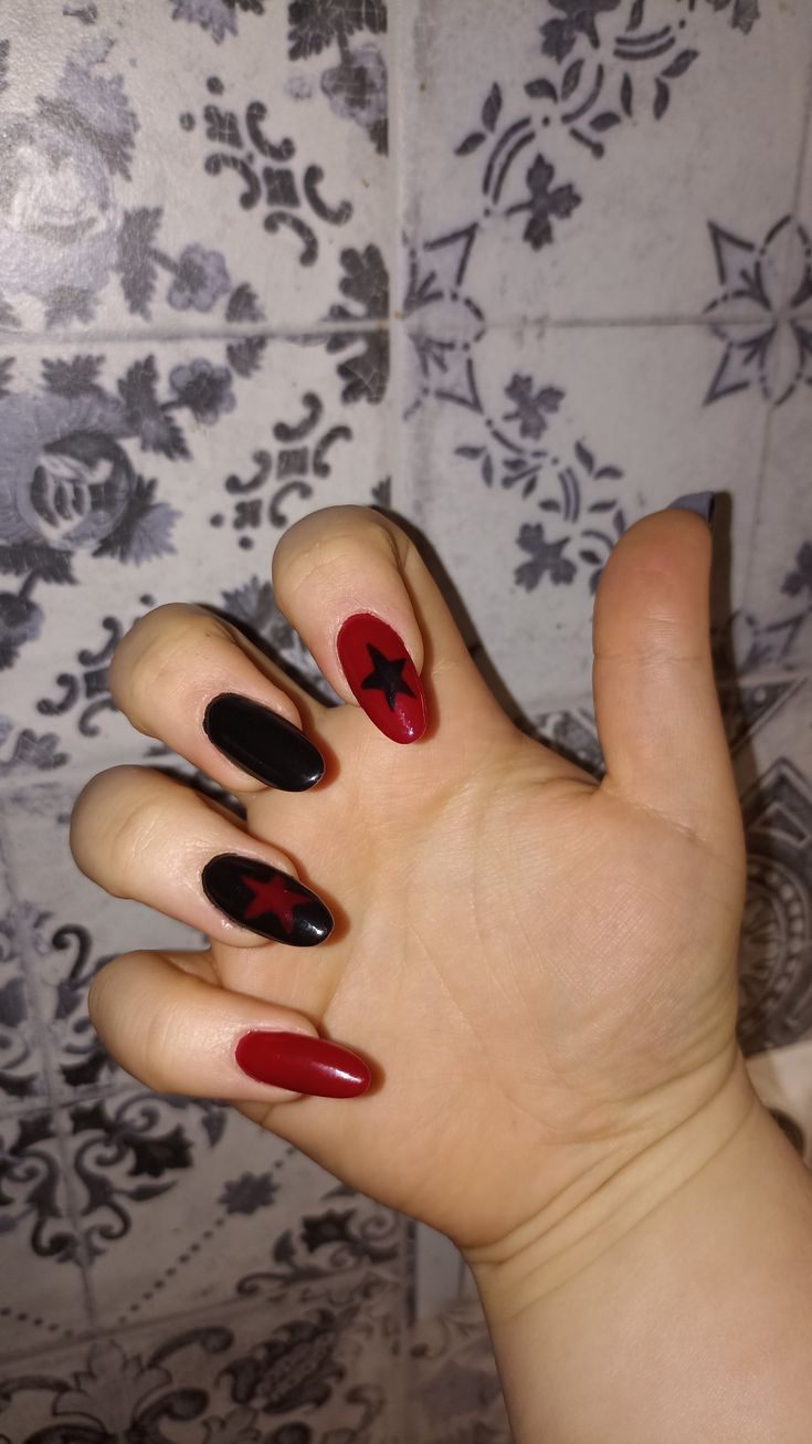 Edgy Black and Red Nail Design with Glossy and Matte Star Accents.