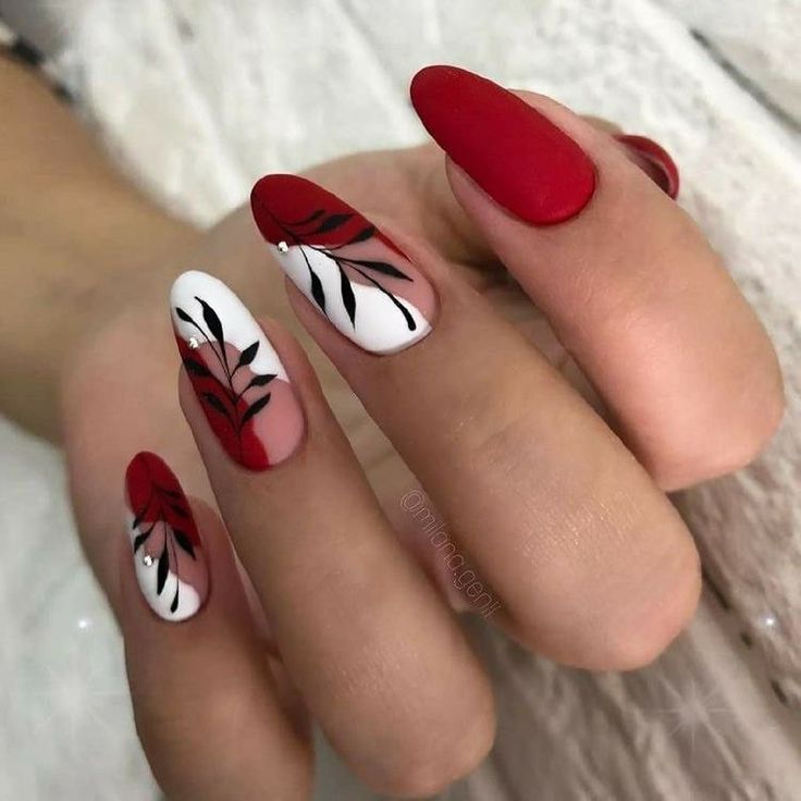 Striking Bold Red and White Nail Design with Leaf Accents and Artistic Detailing