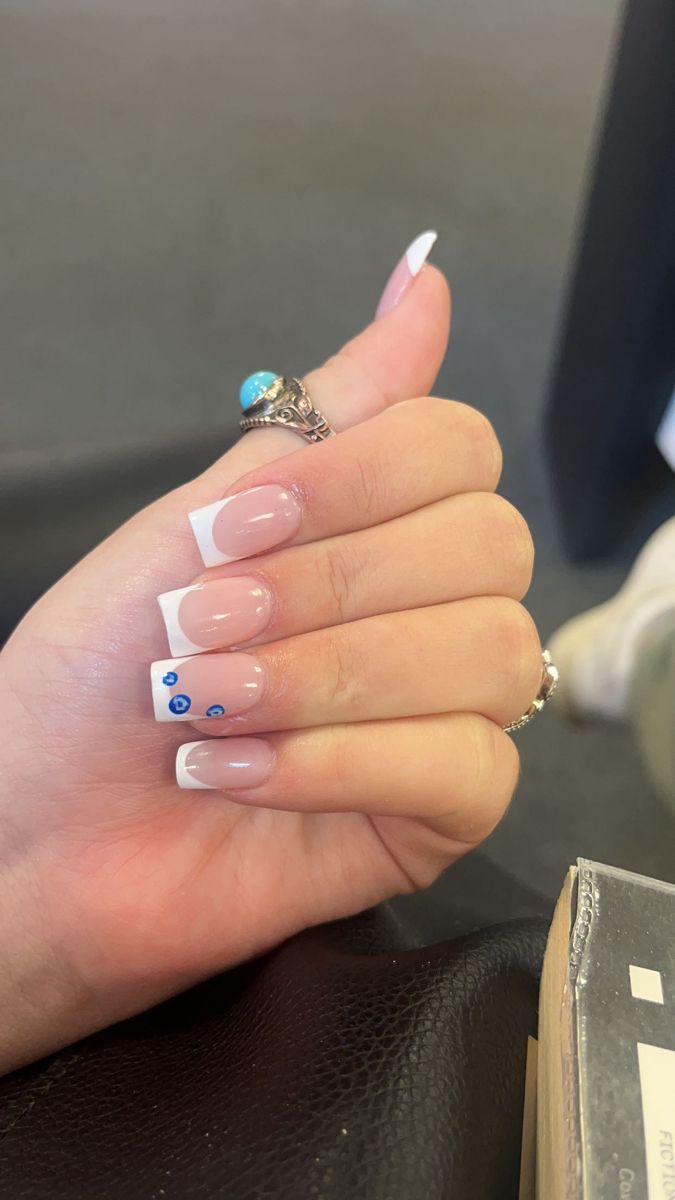 Chic Almond-Shaped French Tip Nails with Nude Base and Delicate Blue Accents.