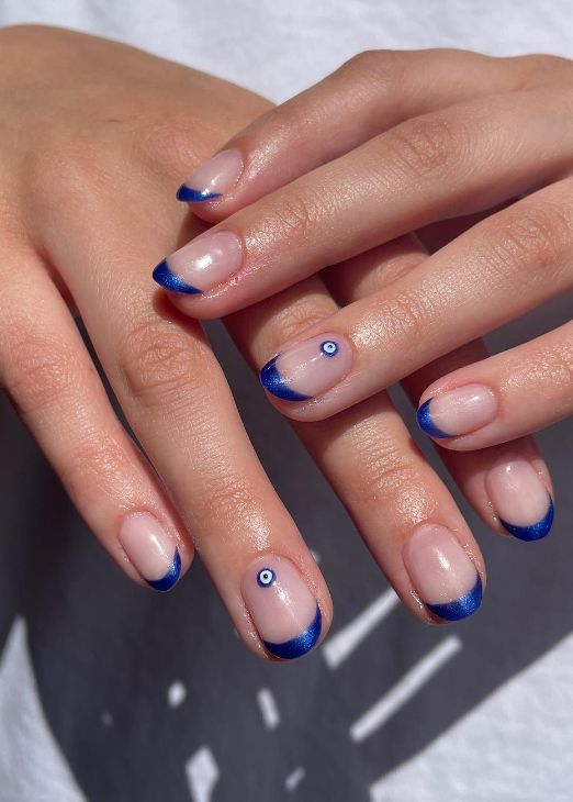 Chic Nude and Navy Nail Design with Delicate Evil Eye Accents.