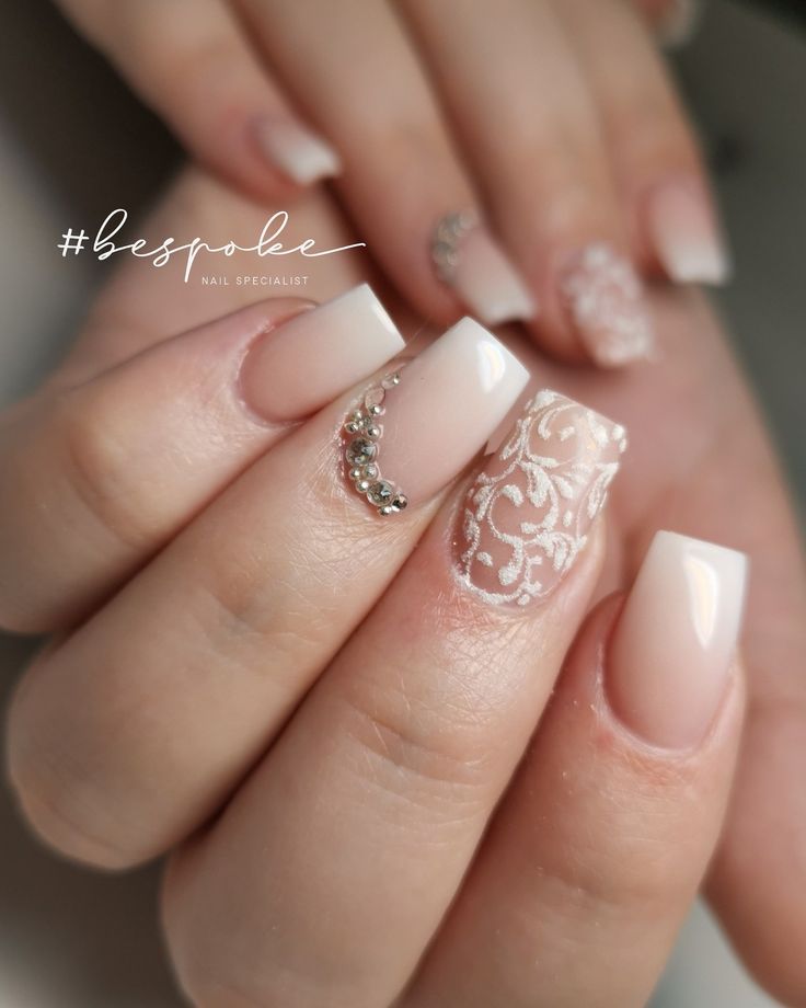 Sophisticated Nude and White Lace Nail Design with Rhinestone Accents.