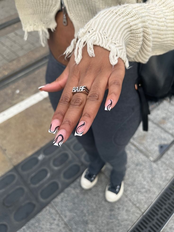 Chic Black and White Swirl Nail Design Enhanced by a Trendy Silver Ring.