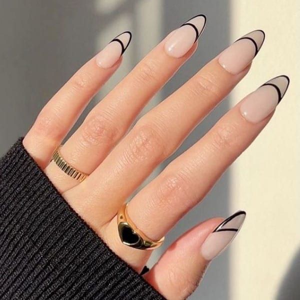 Chic Elongated Nude Nails with Bold Black Tips, Enhanced by Minimalist Rings.