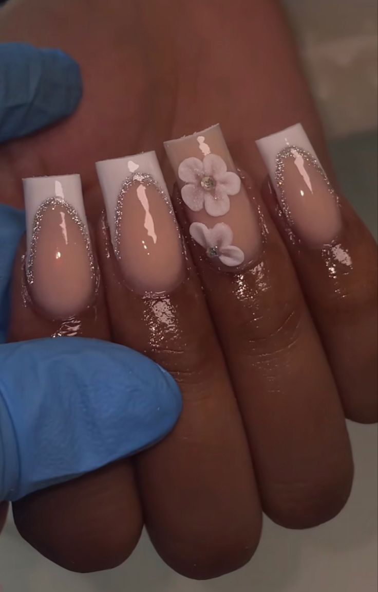 Sophisticated Nude and White Nail Design with Floral and Rhinestone Accents.