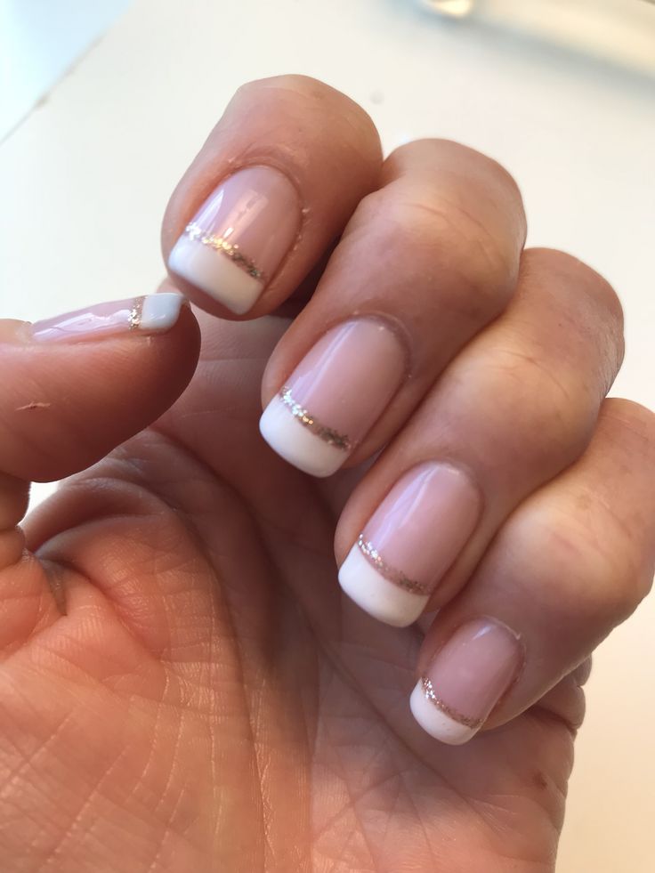 Elegant French Tip Nail Design with Soft Pink and Gold Glitter Accent.