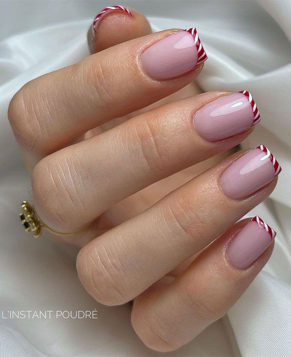 Chic Soft Pink Nail Design with Festive Striped Tips and Red-White Accents