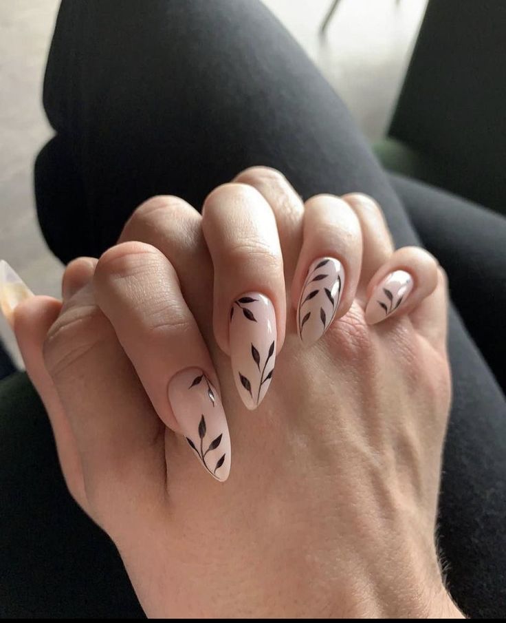 Sophisticated Nail Design: Soft Nude Base with Intricate Black Leaf Patterns.