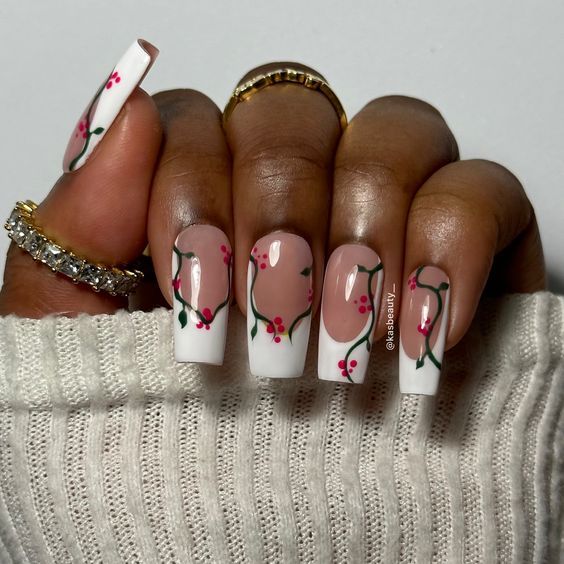 Elegant Floral Nail Design: Delicate Pink Blossoms with Green Vines on a Soft Nude Base with Bold White Tips.