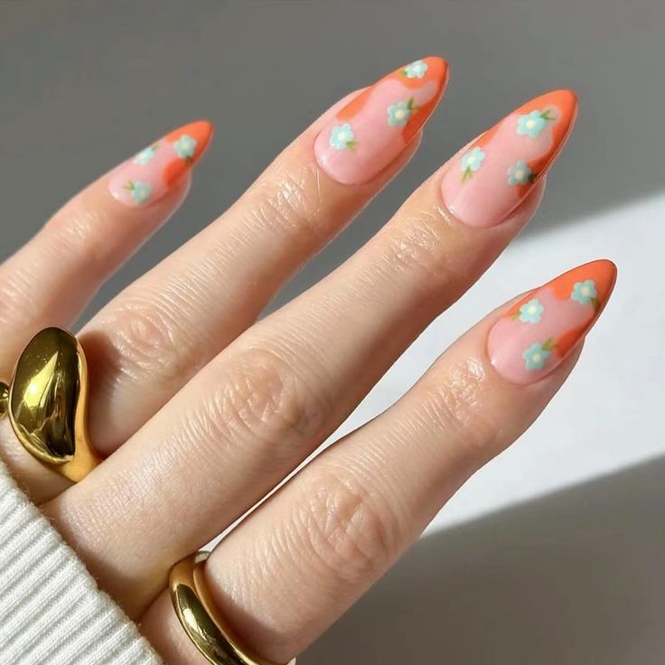 Vibrant Orange-Tipped Almond Nails with Pastel Flower Accents on Sheer Pink Base