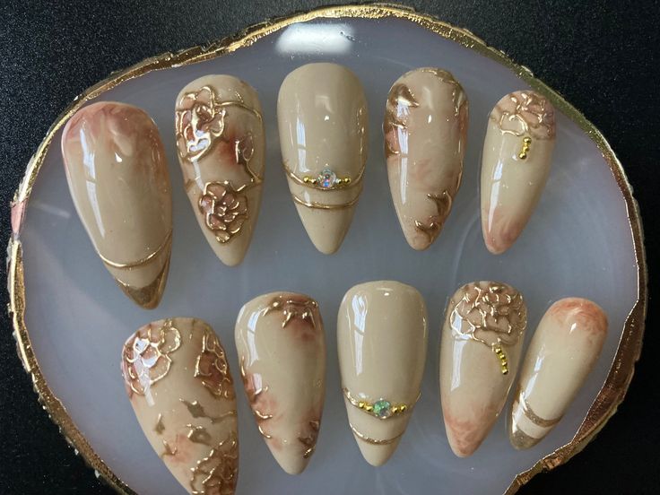 Sophisticated Almond-Shaped Nail Art with Floral Designs and Gold Accents in Soft Beige Ombre.