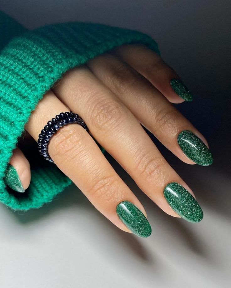 Elegant Sparkling Green Nail Design with Glitter Finish and Contrasting Black Ring.