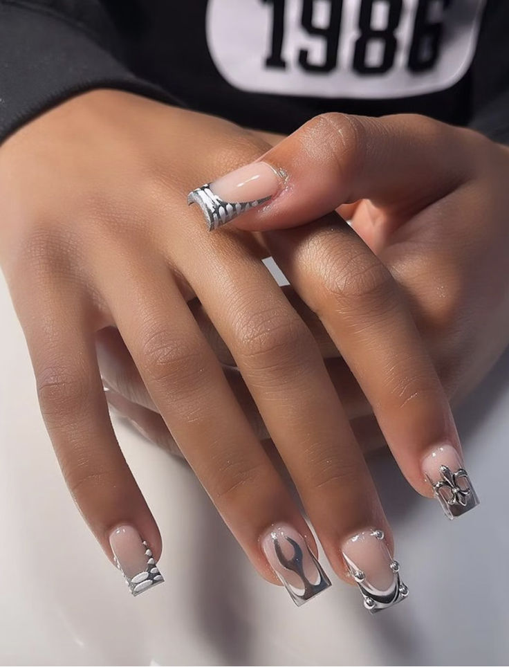 Sophisticated Nail Design with Nude and Silver Accents featuring Artistic Patterns and Textured Finish.