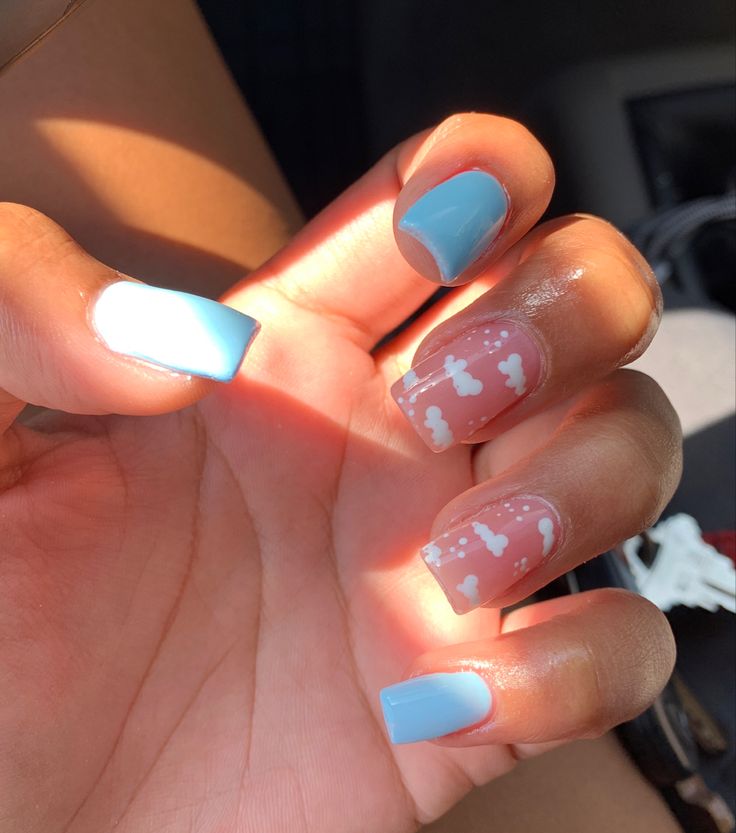 Playful Pastel Nail Design: A Cheerful Mix of Blue and Nude with Whimsical Cloud Patterns.