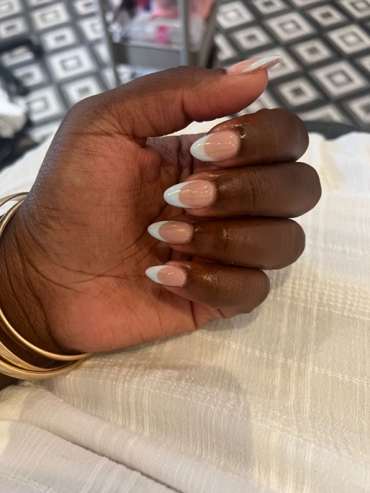 Sophisticated French Tip Manicure with Soft Pink Base and Almond-Shaped Nails Enhanced by Gold Bangles.