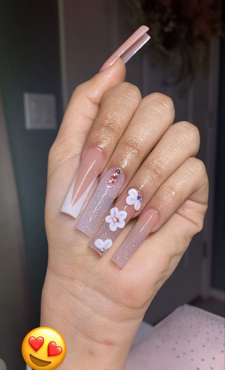 Chic Nail Art: Soft Nude and Sparkling Designs with Floral Embellishments and Gemstones.