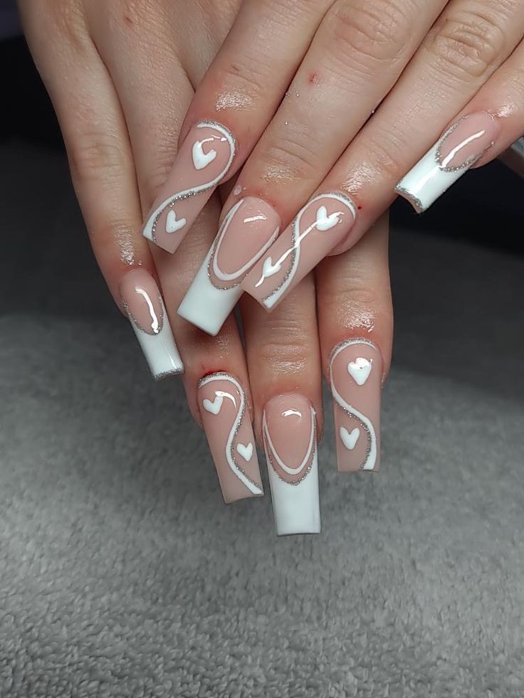 Elegant Nail Design: Nude and White Shades with Heart Patterns and Graceful Swirls for a Romantic Touch.