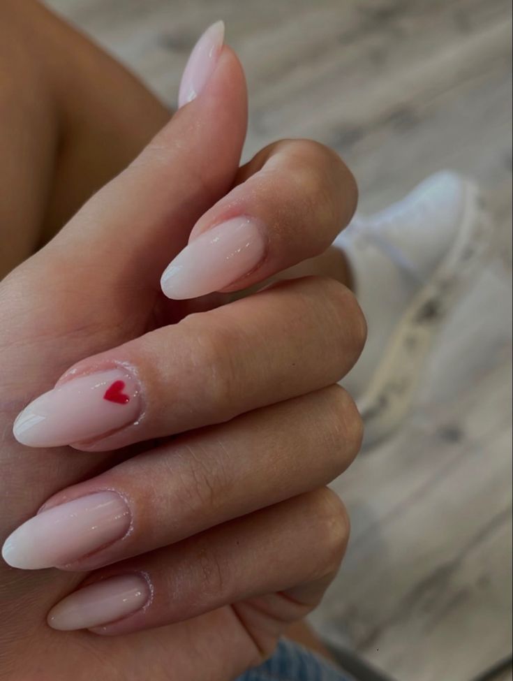 Chic Nude Nail Design with a Playful Red Heart Accent