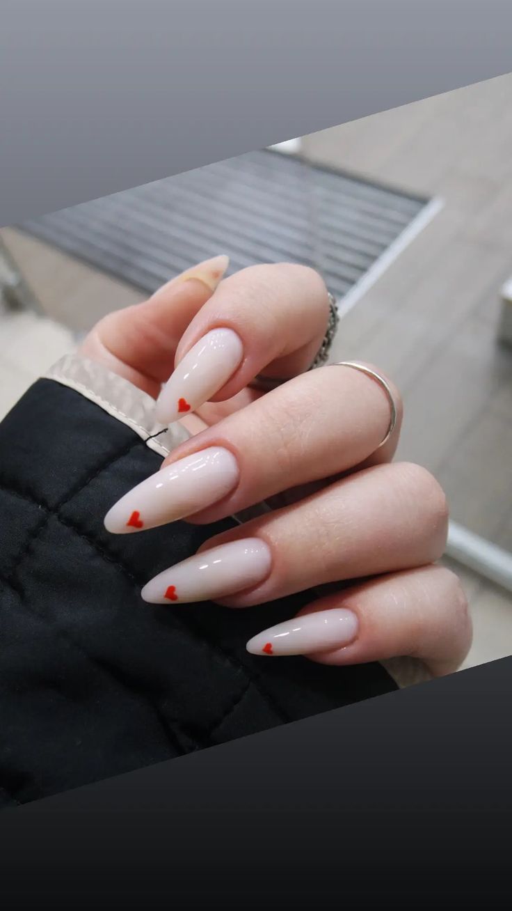 Chic Almond-Shaped Nails with Nude Base and Playful Red Heart Accents