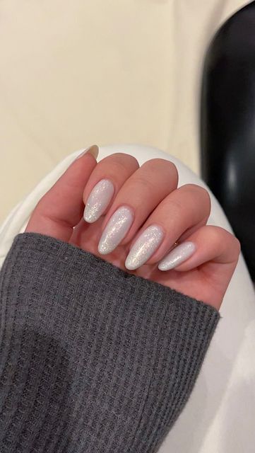 Elegant Almond-Shaped Nails with Pearlescent Shade and Shimmering Glitter Accents.