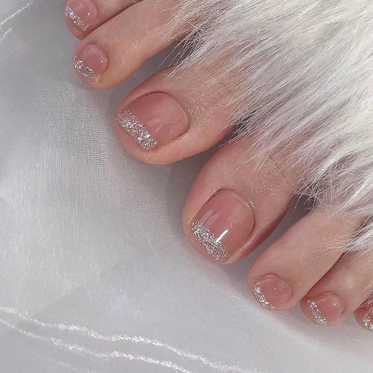 Elegant Sparkling Toenail Design: Soft Nude Base with Shimmering Silver Tips