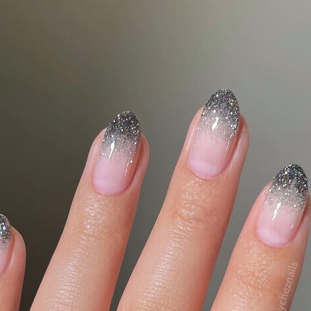 Elegant Gradient Glitter Nails: Sheer Nude Base to Sparkling Silver Tips for Glamorous Occasions.