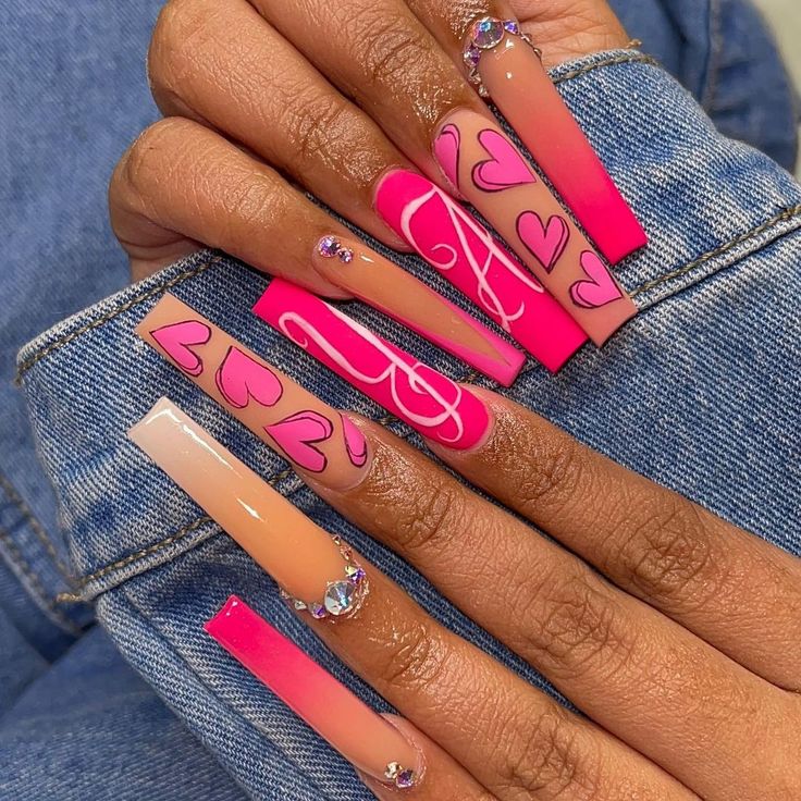 Chic Vibrant Nail Art: Long Acrylics in Pink and Nude with Heart Patterns and Rhinestones.