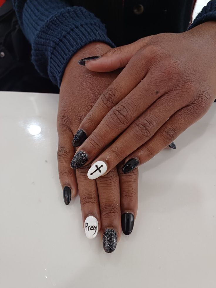 Elegant Nail Design Blending Glossy Black and Sparkly Accents with Bold Symbols for a Fashionable Statement of Faith.